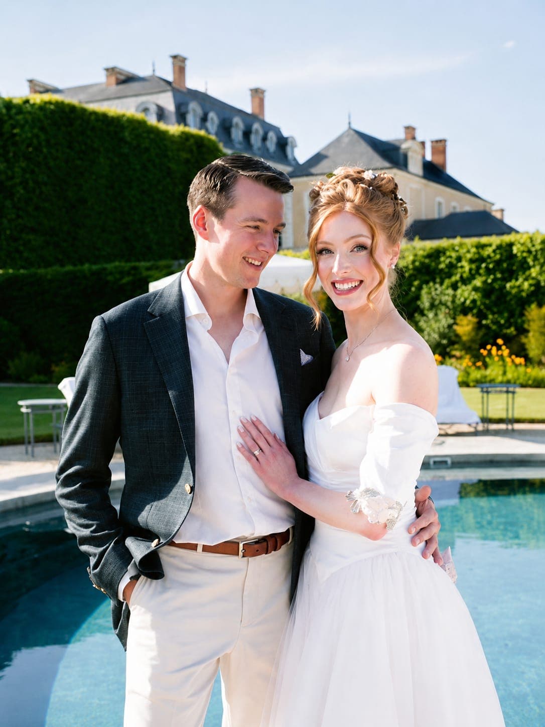 A couple beside a pool, the groom in a navy blazer and white trousers