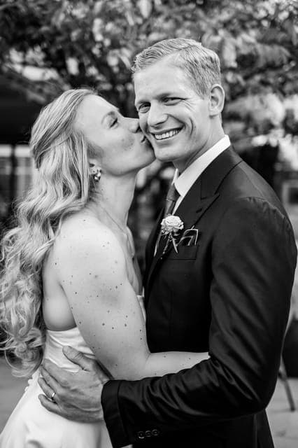 Black and white: a bride kissing the groom's cheek, he in black tie