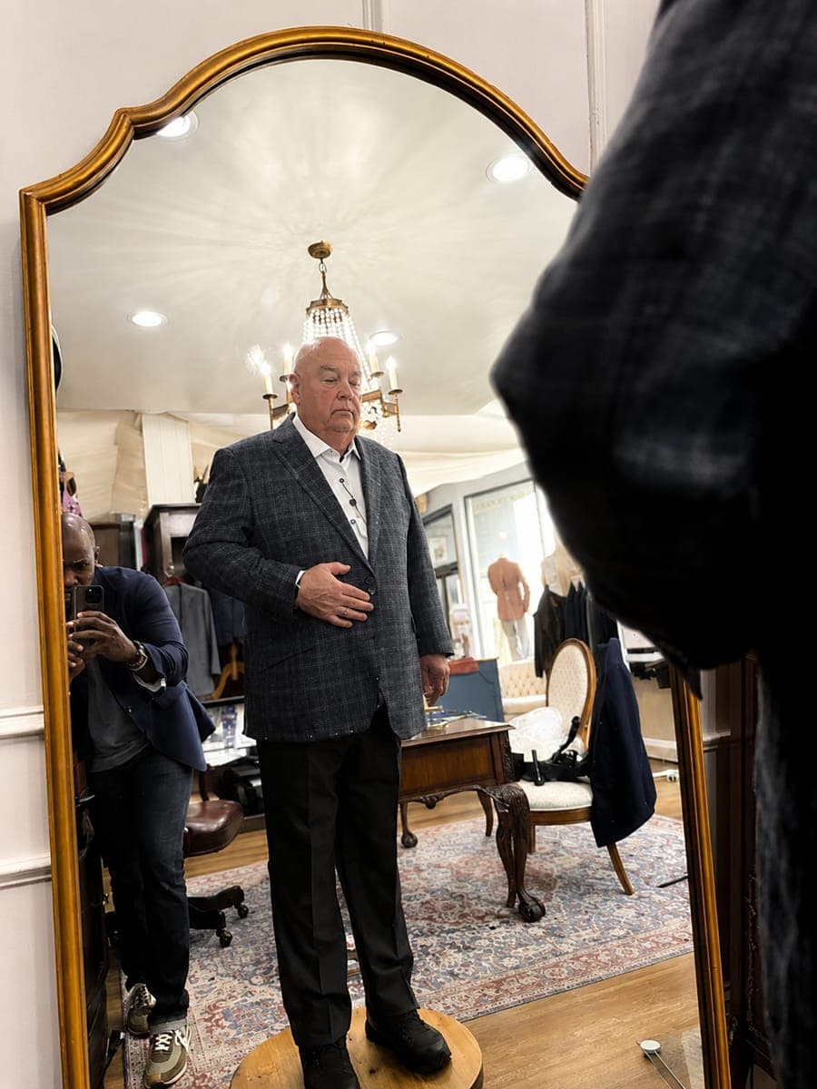 A client in a checked sport coat standing at the fitting mirror