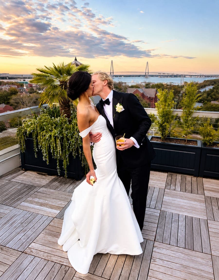 A couple on a rooftop terrace at sunset, the groom in black tie