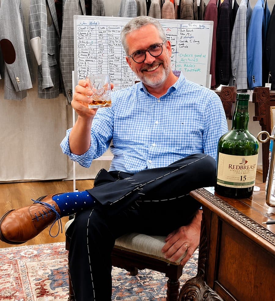 A client reclining with a glass of whiskey, trousers and shoes finished